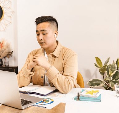 Man in a tan shirt looking at a computer